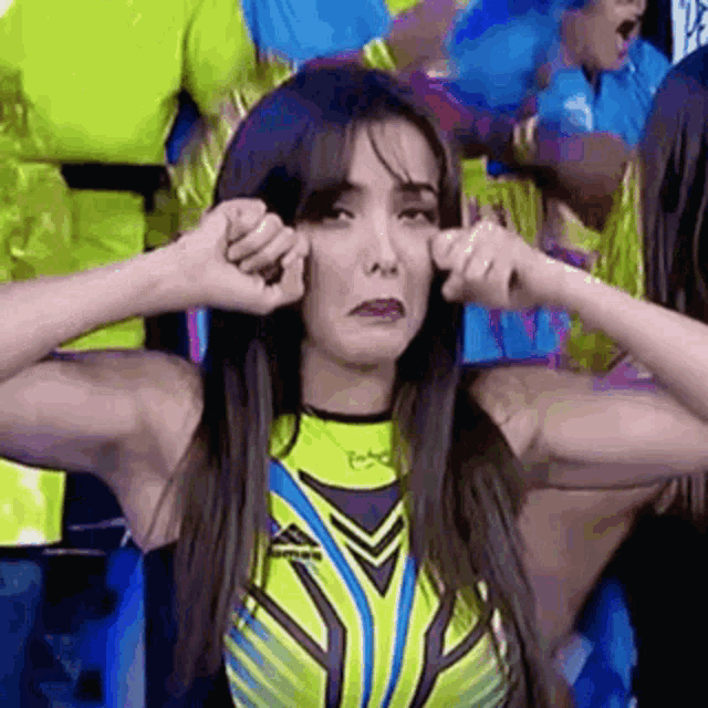 a woman in a yellow and black swimsuit is making a funny face .