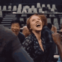 a woman is laughing while sitting in a crowd of people at a party .