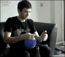 a man is sitting on a couch blowing up a blue balloon with 4gifs.com written on the bottom