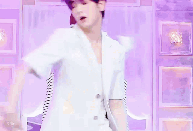 a man with purple hair and a striped shirt is dancing on a stage with other men .
