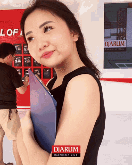 a woman holding a clipboard with the word djarum on her shoulder