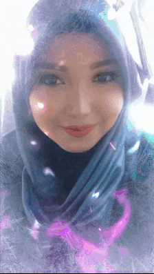 a woman wearing a hijab is smiling with a purple heart in the background