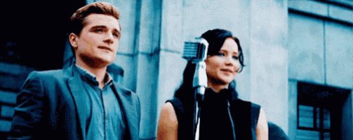 a man and a woman are standing next to each other and talking into a microphone .