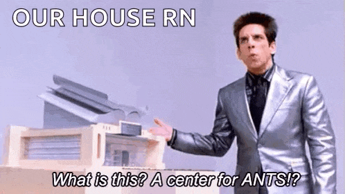 a man in a suit and tie is standing in front of a model of a house with ants .