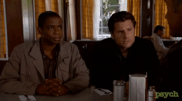 two men sit at a table in a diner with the word psych on the bottom right