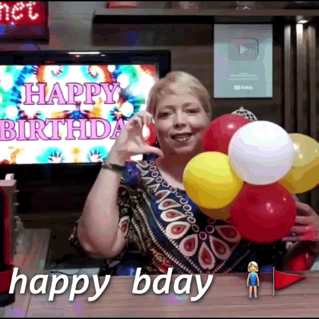 a woman holding balloons in front of a happy birthday sign