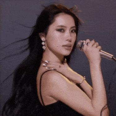 a woman is singing into a microphone and her hair is blowing in the wind