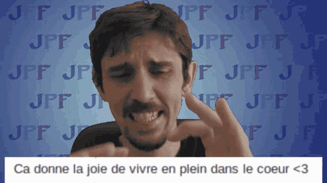a man is making a face in front of a blue background with jpf jpf jpf and jpf jpf
