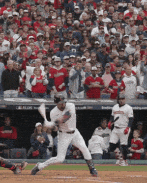 a baseball player swings his bat at a pitch in front of a crowd that says alds on the dugout