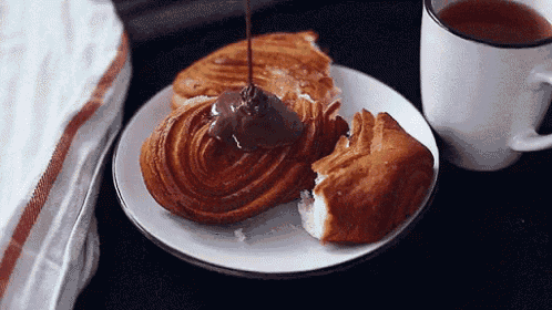 a croissant with chocolate being poured on it