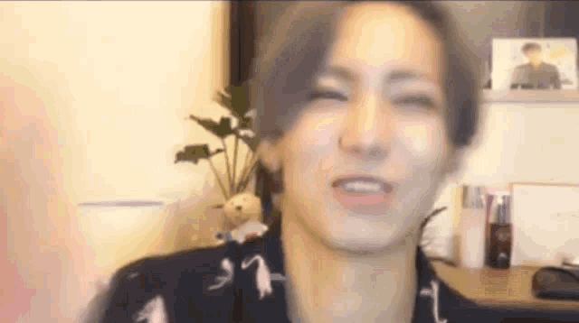 a young man is making a funny face while sitting in front of a computer monitor .