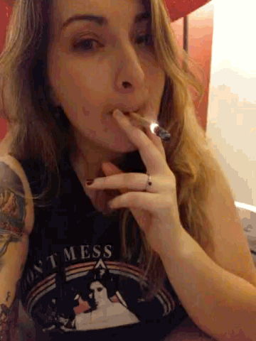 a woman wearing a shirt that says dont mess smoking a cigar