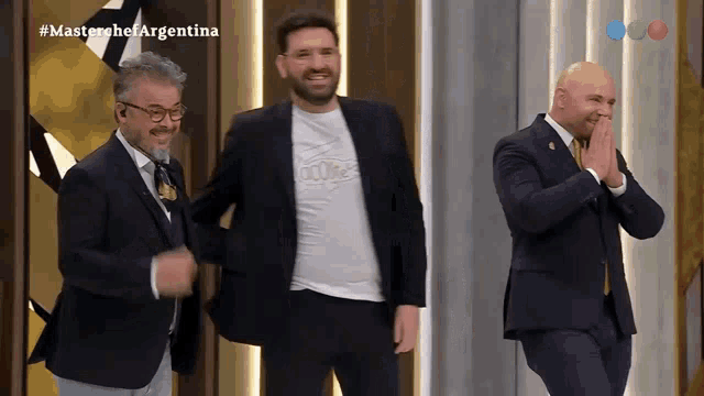 three men are standing on a stage with the words masterchef argentina on the screen