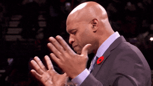 a man in a suit with a poppy pin on his lapel applauds