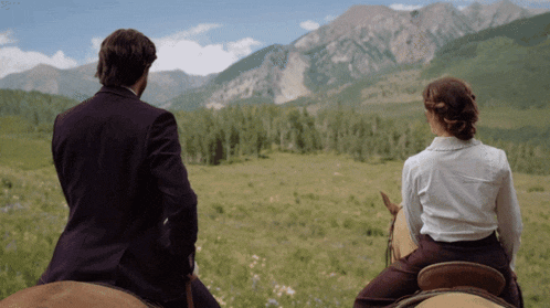 a man and a woman are riding horses in a field