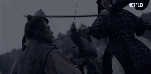 a group of soldiers are fighting each other with swords in a scene from netflix .