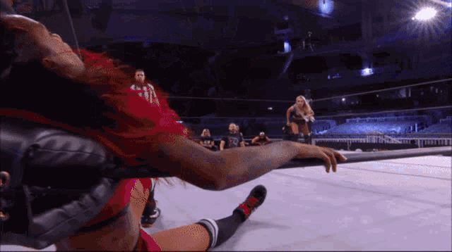 a female wrestler with red hair is laying on the ground