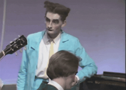 a man in a blue jacket is standing next to another man in a white shirt and tie