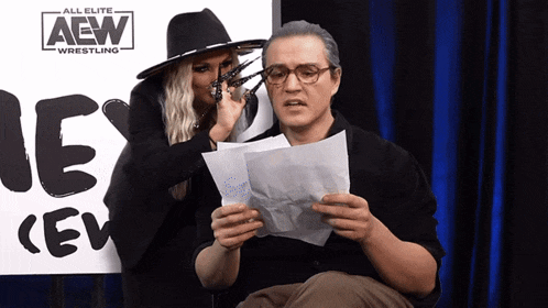 a man sitting in front of a sign that says all elite aew