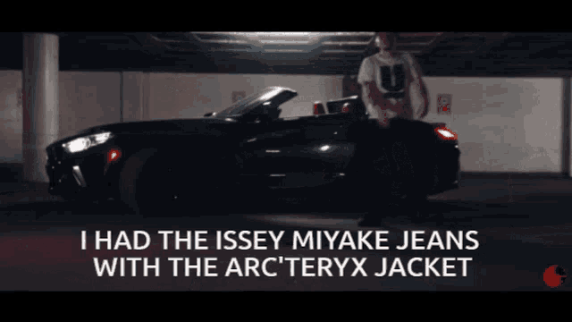 a man is standing in front of a car with the words i had the issey miyake jeans with the arc teryx jacket below him