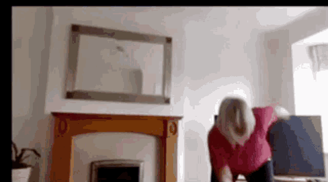 a woman in a red shirt is doing yoga in a living room .