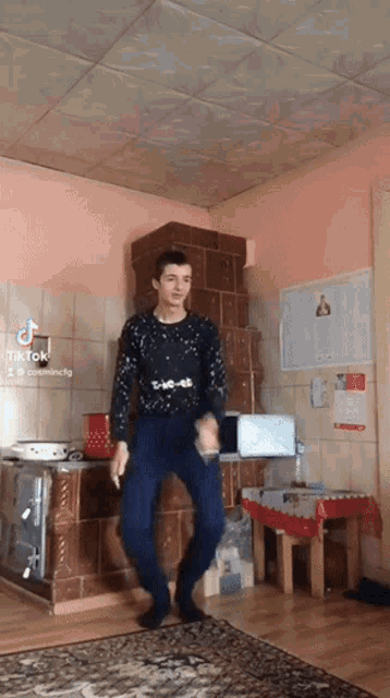 a young man is dancing in a room with a ceiling that has a tile pattern