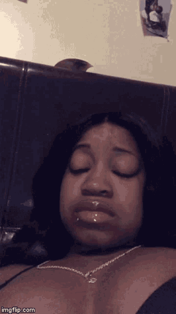 a woman is laying on a bed with her eyes closed and a necklace around her neck .. imgflip.com
