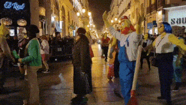 a crowd of people are gathered on a street in front of a store called el real