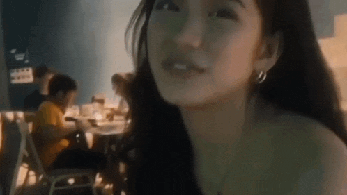 a woman is sitting at a table in a restaurant with a group of people .