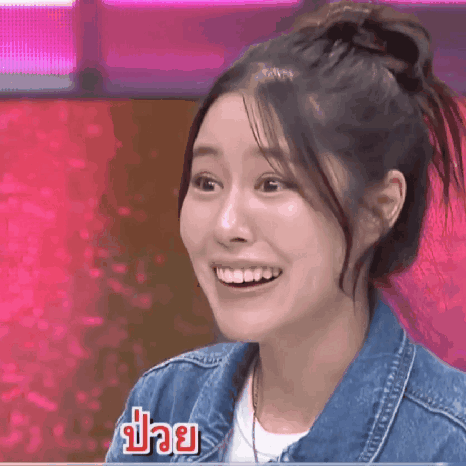 a woman wearing a denim jacket is smiling in front of a pink background ..