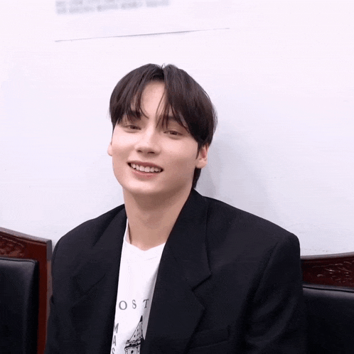 a young man wearing a black jacket and a white shirt that says lost smiles