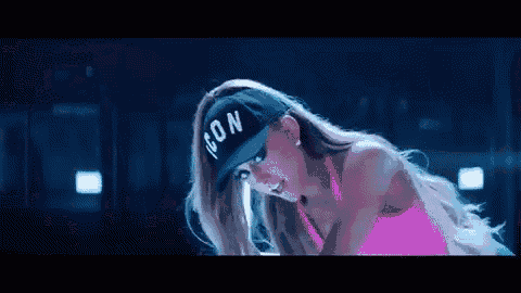 a woman in a pink top and a blue hat is dancing .