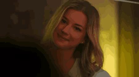 a woman with long blonde hair is smiling and looking at the camera .