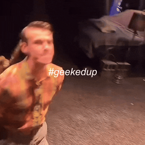 a man with a ponytail is dancing with the hashtag #geekedup behind him