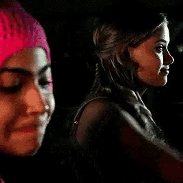 a woman wearing a pink beanie is sitting next to another woman in a car .