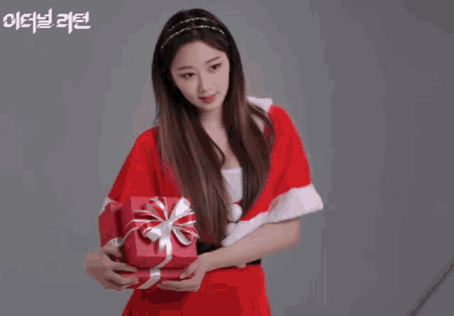 a girl in a santa costume is holding a gift box