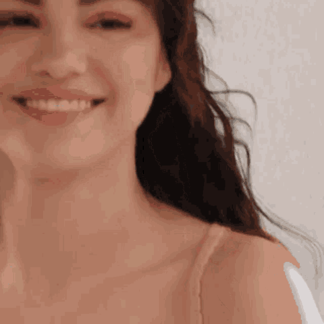 a close up of a woman 's face smiling while wearing a bra .