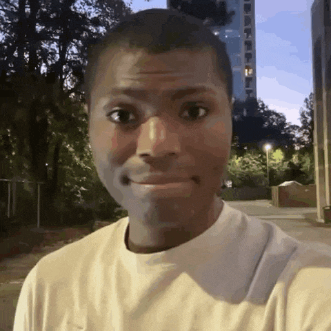 a man in a white shirt is making a funny face while standing in front of a tall building .