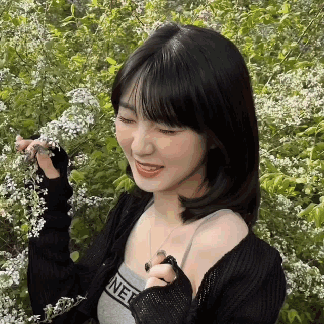 a woman wearing a black cardigan and a tank top with the word chanel on it