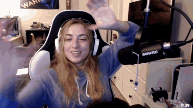a woman wearing headphones and a shure microphone waves her hand