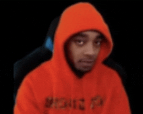 a blurry picture of a man wearing an orange hoodie with a black background