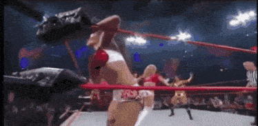 a woman is wrestling in a ring with a referee watching .