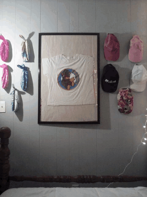 a framed teddy bear t-shirt hangs on a wall