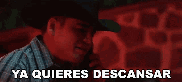 a man wearing a cowboy hat is talking on a cell phone with the words ya quieres descansar behind him