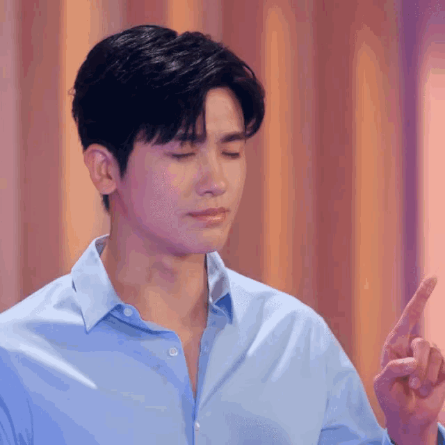 a man in a blue shirt is making a peace sign with his hands
