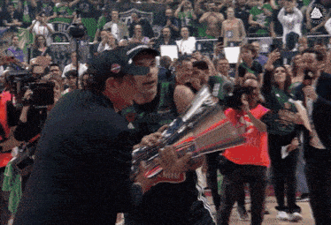 a man holding a trophy in front of a crowd with the word champions on it