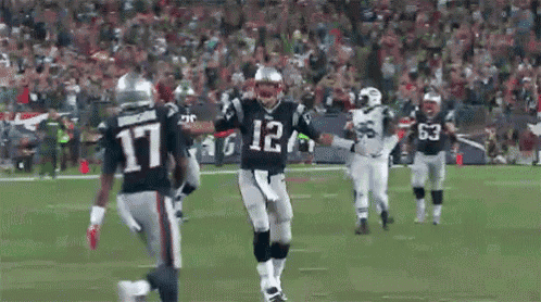 a football player wearing a jersey with the number 12 on it is running on a field .
