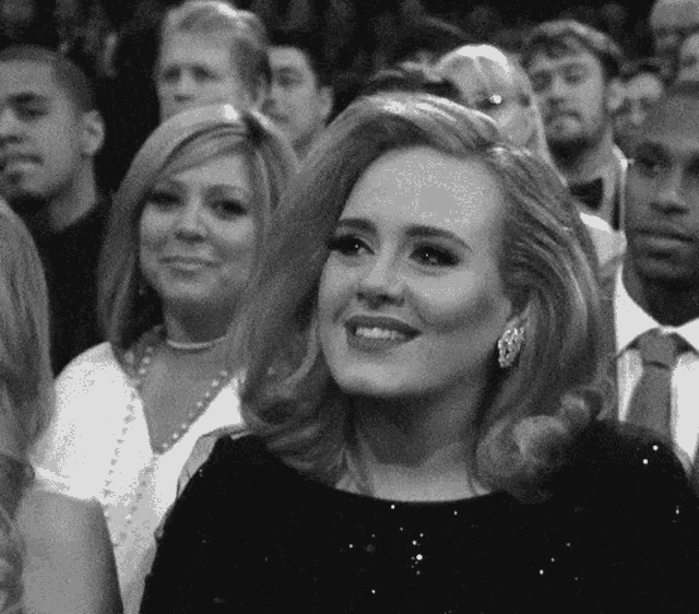 a woman in a black dress is smiling in a crowd of people