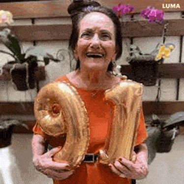 an elderly woman is holding a number balloon in the shape of the number 91 .