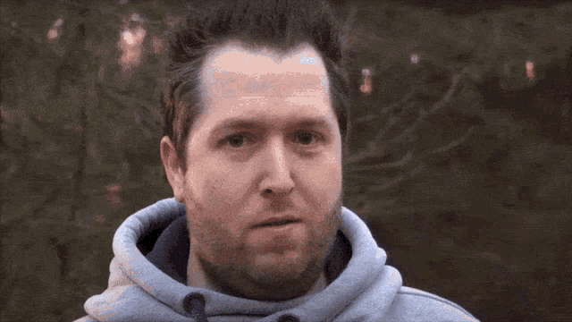 a man with a beard is wearing a gray hoodie